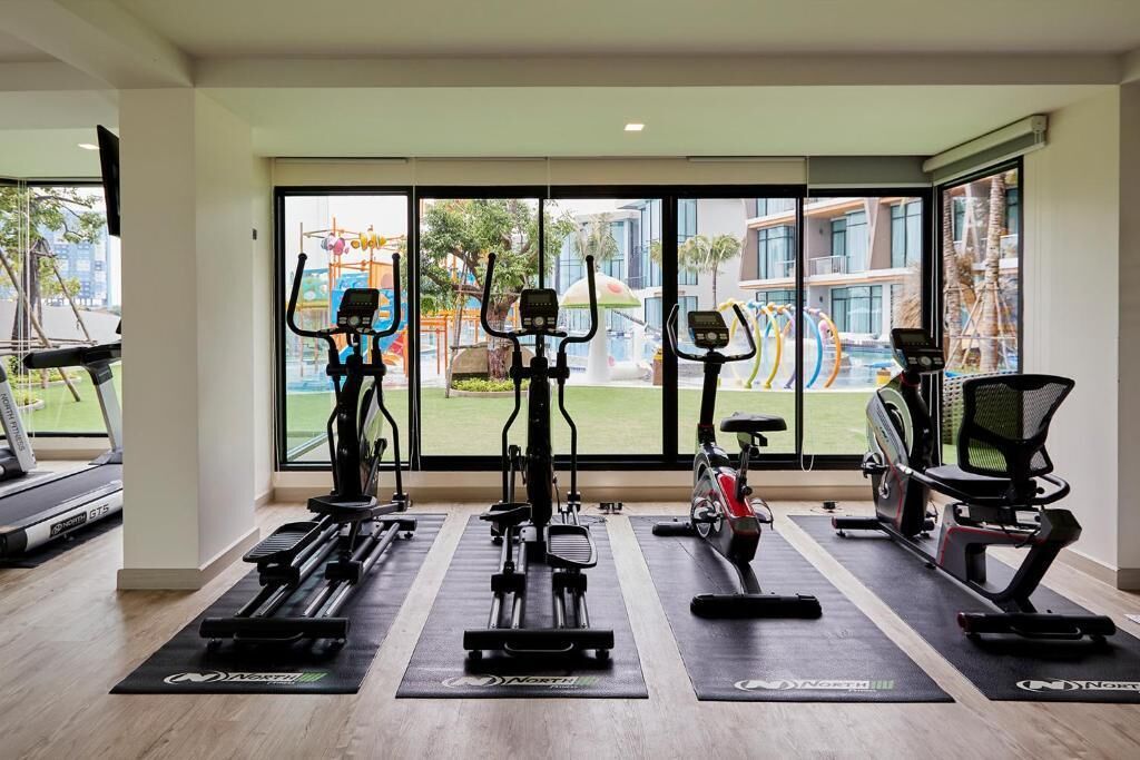 A gym with stationary bikes, treadmills, and exercise mats.