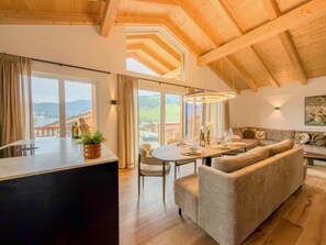A modern interior with a wooden ceiling, a dining area with a round table, and a sofa. - Wonderful ski in-ski out chalet with Sauna (Sankt Lambrecht)
