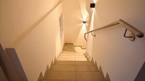 A staircase with a handrail, a light fixture on the wall, and a door at the top. - Wonderful ski in-ski out chalet with Sauna (Sankt Lambrecht)