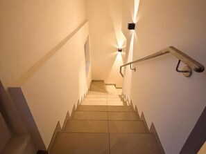 A staircase with a handrail, a light fixture on the wall, and a door at the top. - Wonderful ski in-ski out chalet with Sauna (Sankt Lambrecht)