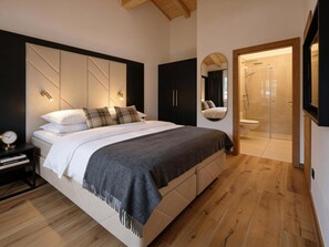 A modern bedroom with a large bed, bedside tables, a mirror, and a walk-in shower. - Wonderful ski in-ski out chalet with Sauna (Sankt Lambrecht)