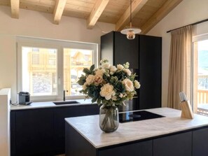 A modern kitchen with a central island, a vase of flowers, and a view of a building outside. - Wonderful ski in-ski out chalet with Sauna (Sankt Lambrecht)