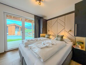 Una habitación de hotel moderna con una cama grande, vistas al campo y una puerta corrediza de vidrio.