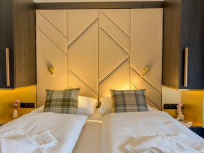 A hotel room with two beds, a geometric headboard, bedside lamps, and a vase with flowers. - Wonderful ski in-ski out chalet with Sauna (Sankt Lambrecht)
