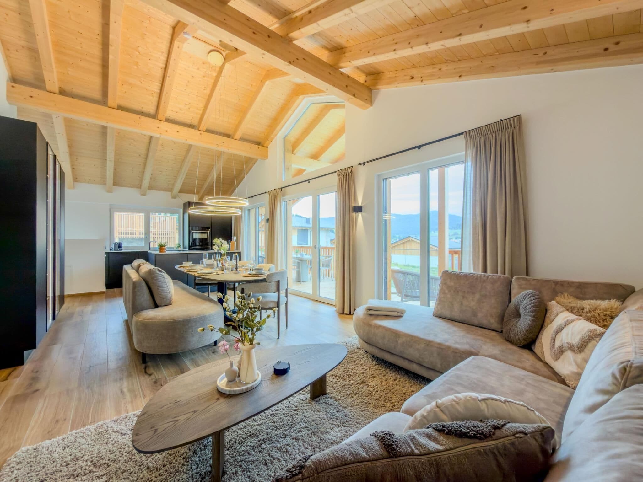 A spacious living area with a high ceiling, a dining table set for four, and a large sofa.