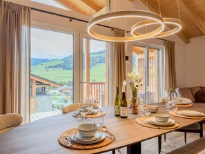 A dining area with a table set for four, large windows, and a view of the countryside. - Wonderful ski in-ski out chalet with Sauna (Sankt Lambrecht)