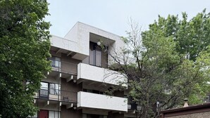 Un edificio residencial de varios pisos con balcones, un patio cubierto de césped y una pequeña zona ajardinada.