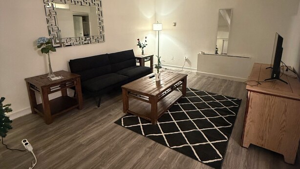 Una sala de estar con sofá, mesa de centro, lámpara y una mesita auxiliar.