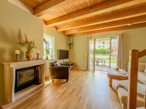 A spacious living room with a fireplace, a sofa, and a dining area. - Chalet with nice garden and wood-fired hot tub (Kötschach-Mauthen)