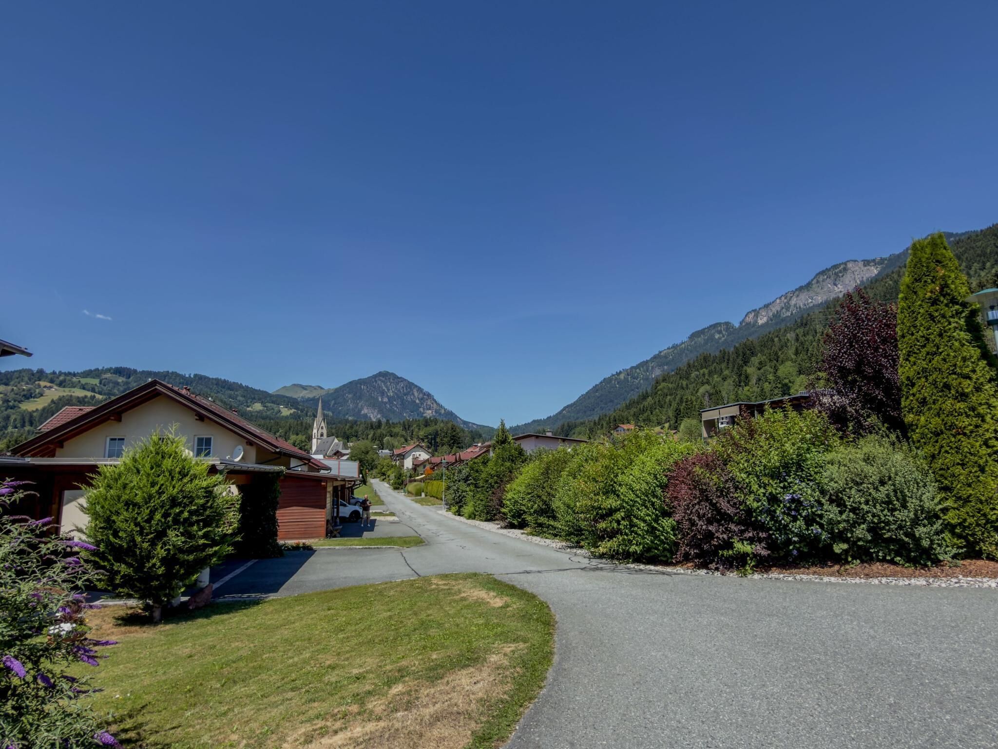 En boligvej med huse, en kirke og bjerge i baggrunden.