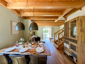 A dining area with a wooden table set for a meal, a staircase, and a wooden cabinet with drawers. - Chalet with nice garden and wood-fired hot tub (Kötschach-Mauthen)