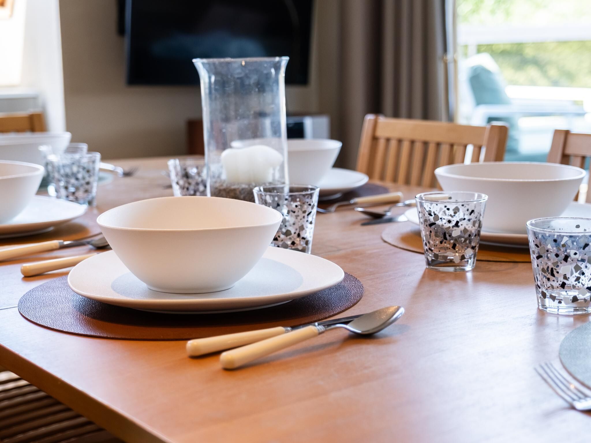 A dining table set with plates, bowls, glasses, and cutlery.