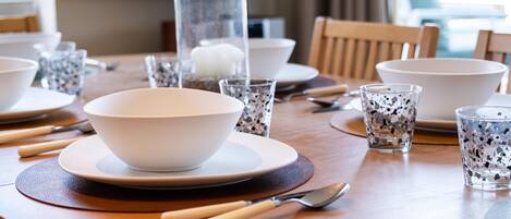 A dining table set with plates, bowls, glasses, and cutlery.