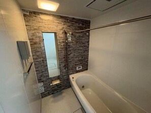 Un bagno moderno con una vasca, una doccia e uno specchio grande.