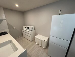 Una cucina moderna con piano cottura integrato, forno a microonde, frigorifero e una serie di pensili.