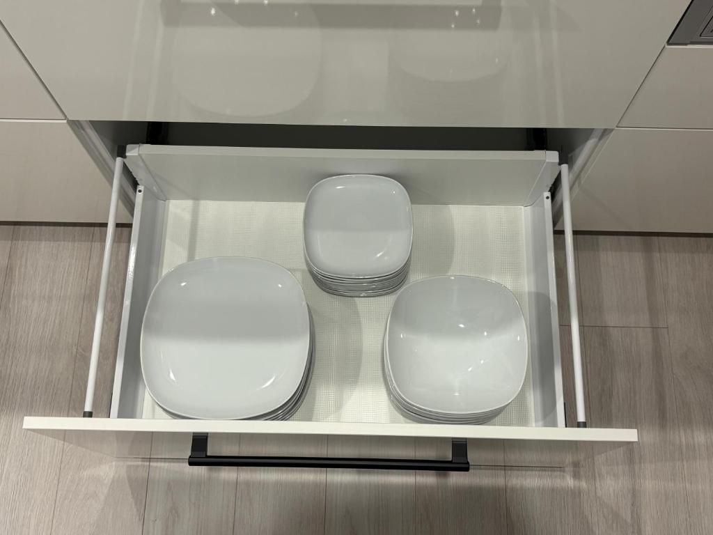 A drawer with three white plates.