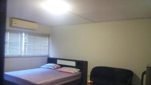 Ein Zimmer mit einem Bett, einem kleinen Tisch, einem Stuhl und einem Fenster mit Jalousien.