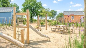 Un'area giochi con scivolo, strutture per arrampicarsi, tavoli da picnic e un'area con sabbia.