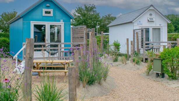 A coastal property with two cabins, one blue and one white, connected by a wooden deck. - Tiny house with garden near the Zeeland coast (Ellemeet)