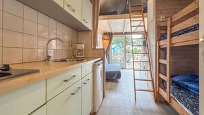 A compact kitchen with a sink, cabinets, and a coffee maker. A wooden ladder leads to a loft bed area. - Tiny house with garden near the Zeeland coast (Ellemeet)