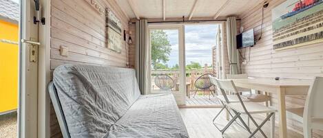 Un interior de cabaña acogedor con una cama, una zona de comedor y un televisor.