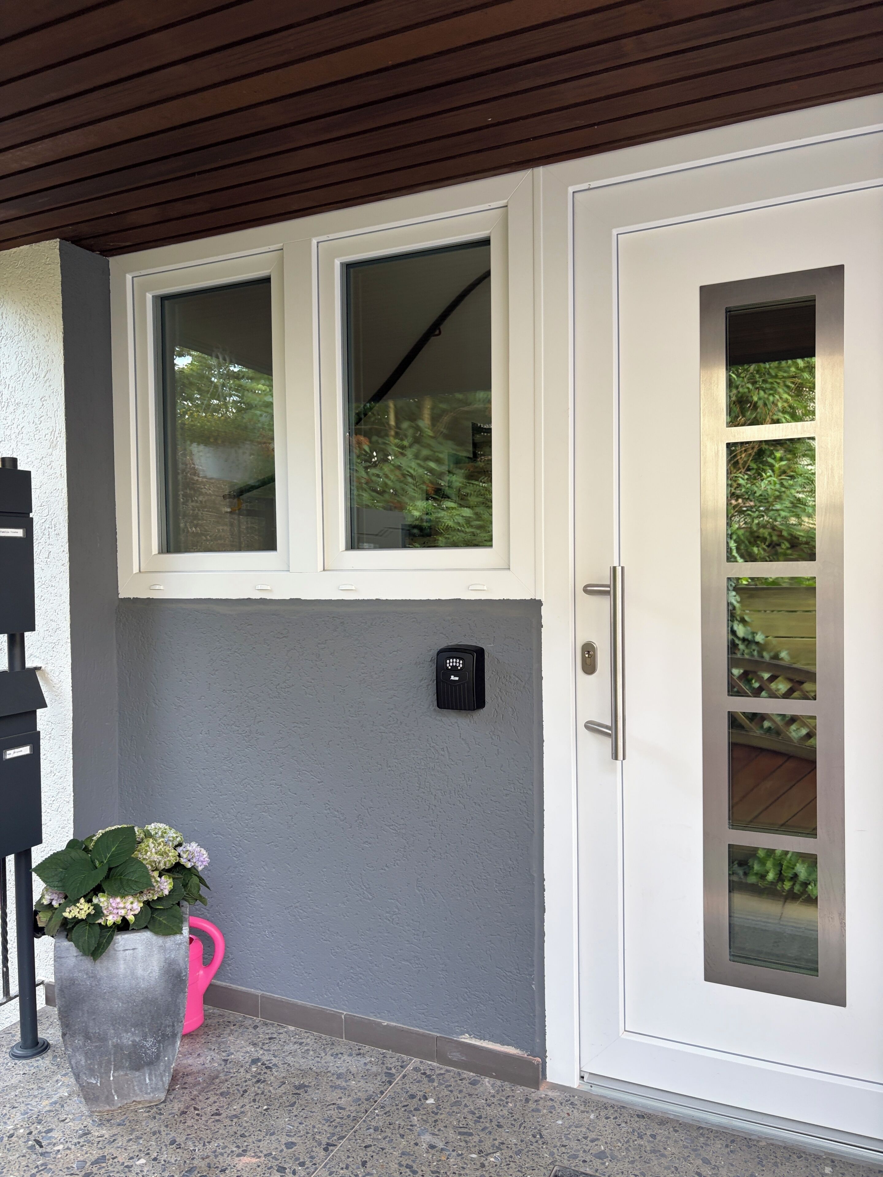 Une entrée moderne avec une porte blanche, une petite fenêtre et un dispositif de sécurité.