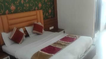 Habitación de hotel moderna con una cama grande, cabecera de madera, pared con diseño verde y un equipo de aire acondicionado.
