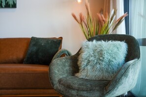 A cozy armchair with a fluffy pillow, a dark green cushion, and a vase with tall grasses. - Yooyen Lakeview | 1 BDRM | Luxury | Views (Queenstown)