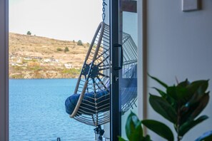 Ein Zimmer mit Blick auf ein Gewässer und eine Hügelkuppe.