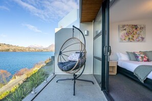 A balcony with a hanging chair, a bed, and a painting. - Yooyen Lakeview | 1 BDRM | Luxury | Views (Queenstown)