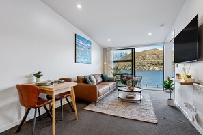 Ein modernes Wohnzimmer mit Essbereich, einer Couch, einem Couchtisch und einem großen Fernseher.
