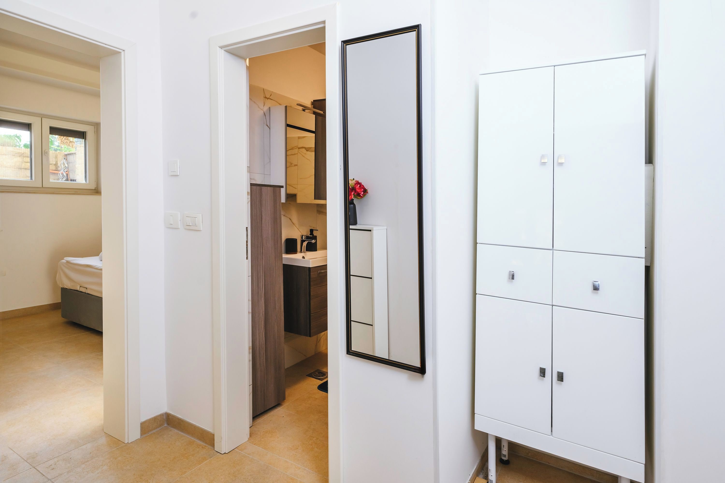Un dormitorio con cama, un baño con lavamanos y espejo, y un armario.
