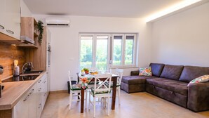 A modern kitchen with white cabinets, a dining table with chairs, and a brown leather sofa. - Sanbaldo 1BR Terrace Apartment Koper (Koper)