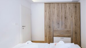 A bedroom with a bed, a wooden wardrobe, and a white door. - Sanbaldo 1BR Terrace Apartment Koper (Koper)