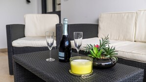 A wicker table with a bottle, glasses, a candle, and a potted plant. - Sanbaldo 1BR Terrace Apartment Koper (Koper)