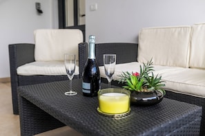 A wicker table with a bottle, glasses, a candle, and a potted plant. - Sanbaldo 1BR Terrace Apartment Koper (Koper)