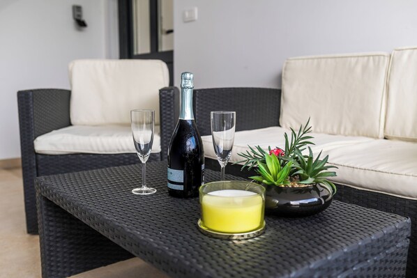 A wicker table with a bottle, glasses, a candle, and a potted plant. - Sanbaldo 1BR Terrace Apartment Koper (Koper)