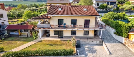 Une maison à deux étages, avec un toit en tuiles, un balcon et une allée pavée.