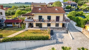 A two-story house with a balcony, a paved driveway, and a well-maintained garden. - Sanbaldo 1BR Terrace Apartment Koper (Koper)