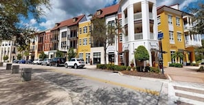 A multi-story hotel with a central courtyard, outdoor seating, and a variety of commercial spaces on the ground floor. - La Piazza 3br/3 ba top floor condo overlooking magnificent Oratory & Town Center (Ave Maria)