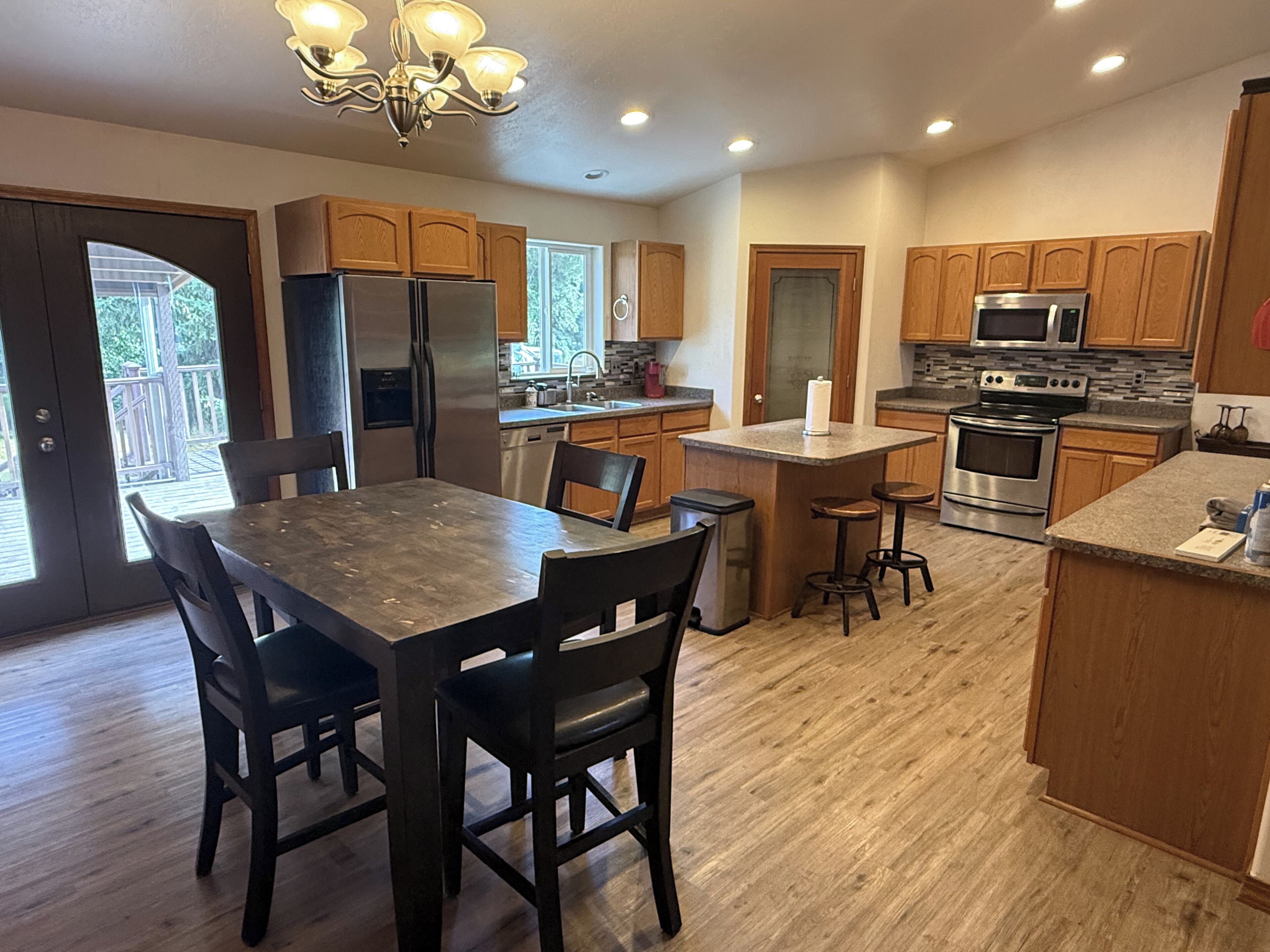 A modern kitchen with wooden cabinets, stainless steel appliances, and a central island with stools.