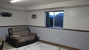 A room with a large window, a leather chair, and a patterned rug. - Perfect 3-bedroom house centrally located in the Flathead. (Kalispell)