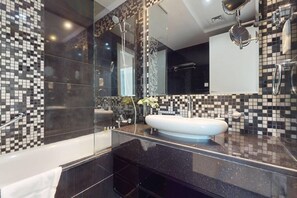 Een moderne badkamer met een douche met glazen wand, een witte wastafel en een grote spiegel.