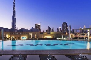 A rooftop pool with a view of the Burj Khalifa and other buildings. - Cozy 1 Bedroom l Burj Views from Pool Areal (Business Bay)