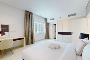 A hotel room with a bed, a desk, a wardrobe, and a window. - Cozy 1 Bedroom l Burj Views from Pool Areal (Business Bay)