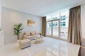 A modern living room with a sofa, coffee table, and a potted plant. - Cozy 1 Bedroom l Burj Views from Pool Areal (Business Bay)
