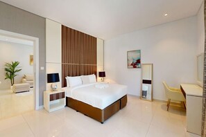 A modern hotel room with a large bed, bedside tables, a desk, a chair, a mirror, and a potted plant. - Cozy 1 Bedroom l Burj Views from Pool Areal (Business Bay)