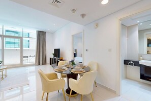 Een moderne hotelkamer met een eethoek, een groot raam en een badkamer met een spiegel en wastafel.