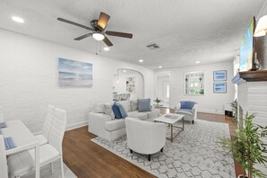 A spacious living room with a ceiling fan, a white sofa set, a coffee table, and a patterned rug. - West Palm Beach Home (West Palm Beach)