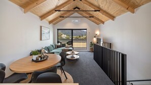 Un interior moderno con techo de madera, un área de comedor con mesa y sillas redondas, un sofá y un balcón con vistas.
